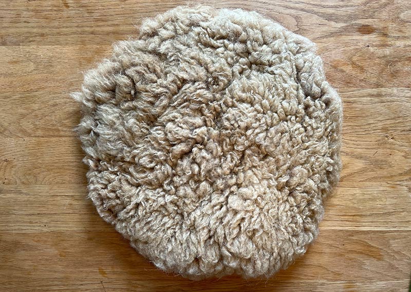 Gutschein – Fellfilzen Workshop: Ein kleines Schafwoll-Sitzfell filzen. Halbtagesworkshop von 14-18 Uhr. Inklusive Verpflegung und sämtliches Material. Keine Vorkenntnisse nötig. Du hast in diesem Workshop Zeit um ein kleines rundes Schafwollfell zu filzen. Passend für Stühle. Ein weiches, flauschiges Fell bereichert jede Seele und verströmt die richtige Portion «Gemütlichkeit» in deinem Zuhause. Gefilzte Felle sind Zeugen vom freien Leben der Schafe, sie sind pur, natürlich und aus 100 % Wolle, ganz ohne Leder. Ich bringe dir Schritt für Schritt bei, wie du ein eigenes, handgefertigtes Schaffell herstellst. Dabei werden wir die geschorene, unbehandelte Rohwolle von glücklichen Schafen mit Wasser und Seife so verarbeiten, dass ihre Felloptik möglichst erhalten bleibt. Die Rückseite darfst du individuell gestalten. Fellfilzen ist ein schmutziger aber sinnlicher Job.