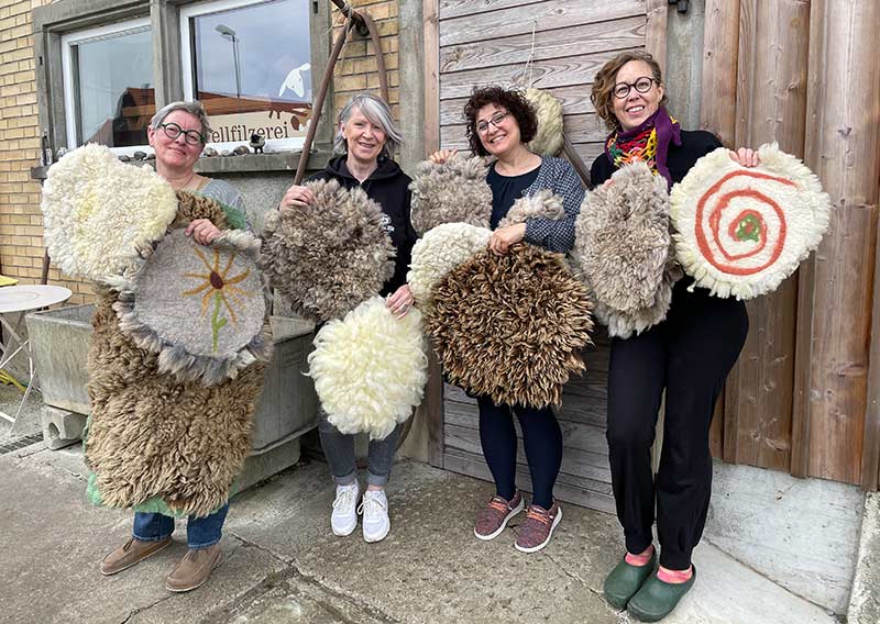 Gutschein – Fellfilzen Workshop: Ein kleines Schafwoll-Sitzfell filzen. Halbtagesworkshop von 14-18 Uhr. Inklusive Verpflegung und sämtliches Material. Keine Vorkenntnisse nötig. Du hast in diesem Workshop Zeit um ein kleines rundes Schafwollfell zu filzen. Passend für Stühle. Ein weiches, flauschiges Fell bereichert jede Seele und verströmt die richtige Portion «Gemütlichkeit» in deinem Zuhause. Gefilzte Felle sind Zeugen vom freien Leben der Schafe, sie sind pur, natürlich und aus 100 % Wolle, ganz ohne Leder. Ich bringe dir Schritt für Schritt bei, wie du ein eigenes, handgefertigtes Schaffell herstellst. Dabei werden wir die geschorene, unbehandelte Rohwolle von glücklichen Schafen mit Wasser und Seife so verarbeiten, dass ihre Felloptik möglichst erhalten bleibt. Die Rückseite darfst du individuell gestalten. Fellfilzen ist ein schmutziger aber sinnlicher Job.