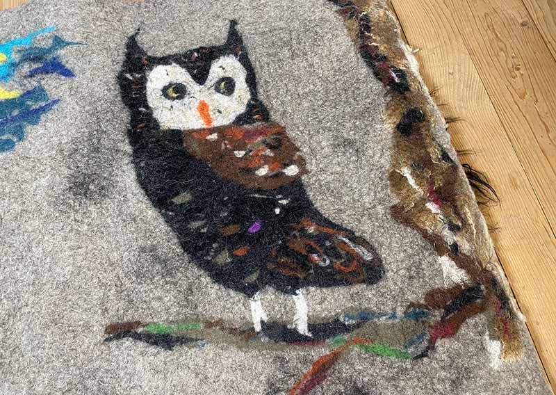 Filzfell aus drei Schafrassen – Ein kunstvolles Unikat.
Dieses aussergewöhnliche Filzfell vereint die Wolle von drei verschiedenen Schafrassen zu einem harmonischen Kunstwerk. Die dunklen, langen Strähnen des Ouessantschafs (ZH) bilden den Mittelpunkt, umrahmt vom tiefschwarzen, leicht gelockten Walliser Landschaf (VS) und dem knuffig-weichen, elfenbeinfarbenen Spiegelschaf (GR). Die Mischung aus Farben und Strukturen macht dieses Stück einzigartig.

Ob als Fellteppich im Wohnbereich, gemütliche Sofadecke oder wärmende Spiel- und Leseoase auf kalten Böden – dieses handgefertigte Unikat bringt Wärme und Charakter in dein Zuhause. Die graue Filzrückseite sorgt für Stabilität und Robustheit, während eine liebevoll gestaltete Eule darauf das Design abrundet.

Ein kunstvolles Naturstück, das nicht nur gemütlich, sondern auch ein echter Blickfang ist.