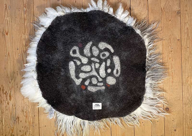 Die Wilde. 
Dieses besondere Filzfell stammt vom Drenthe Heideschaf – ursprünglich, lebendig und zugleich überraschend weich.
An den Rändern habe ich es mit feiner Romneywolle ergänzt – ein harmonisches Zusammenspiel aus Natürlichkeit und Eleganz.

Das Fell begeistert mit seinen langen, leicht gewellten Haaren in Holunderblütenweiss und Nebelgrau, durchzogen von silbrigen Schattierungen, die je nach Licht schimmern.
Ein echtes Liebhaberstück mit charaktervollem Charme – perfekt für die Gartenbank, den Lesesessel oder einfach als Blickfang in deinem Zuhause.

Wichtig zu wissen: Dieses Naturfell ist lebendig in seiner Ausstrahlung – beim Durchkämmen mit den Fingern können einige Haare zurückbleiben. Das macht es umso authentischer und verleiht ihm den Zauber, als hätte man ein kleines Stück Natur bei sich zu Hause.
Optisch bleibt „Die Wilde“ immer in Bestform und wird dich lange begleiten.