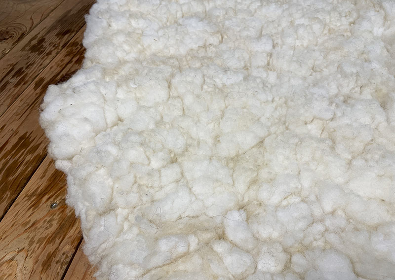 Die Liegewiese. 
Na, wenn das kein Prachtstück ist! Dieses Filzfell misst stattliche 1,75 × 1 Meter – das grösste, das je die Werkstatt der Fellfilzerei Jawoll verlassen hat.
Gefertigt aus feinster Romney-Wolle in Schafsmilchweiss, kräftig und weich zugleich, und veredelt mit einem Kreis aus Locken der Walliser Schwarznasenschafe – als wäre ein Stück Alpenpoesie eingefilzt.

Mehrere Schafe aus dem Kanton Bern haben hier ihre Wolle gespendet – und das Ergebnis ist einfach jawollig schön. Dieses Fell ist so dick, weich und robust, dass es fast schon nach draussen ruft: „Mach’s dir gemütlich!“

Ob auf dem grossen Sofa, im Bett oder direkt auf dem Boden – diese Liegewiese lädt zum Lesen, Träumen und Musiklauschen ein. Kinder lieben sie genauso wie Erwachsene, die sich zwischendurch eine sanfte Wolke unterlegen möchten.

Ein echtes Unikat – und ja, das darf man diesem Wunderwerk auch im Preis ansehen.
Mit einem Augenzwinkern: So ein Stück entsteht wohl nur einmal im Leben …