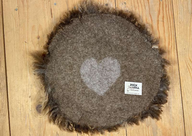 Sitzfell vom Bergschaf – Schokomelange mit Herz.
Dieses Sitzfell stammt von einem Bergschaf aus Graubünden – ein kuschliges Stück Natur in Schokoladenbraun mit zarten Sahnetupfen. Die feine Melierung erinnert an eine Tasse heisse Schokolade mit Rahmhaube – einfach zum Reinsetzen schön.

Die Wolle ist weich, dicht und herrlich knuffig, ideal zum gemütlichen Sitzen und Verweilen. Auf der Rückseite ist ein Herz eingefilzt – als kleiner Gruss von der Fellfilzerei und vielleicht auch ein bisschen als Liebeserklärung an das Schaf.