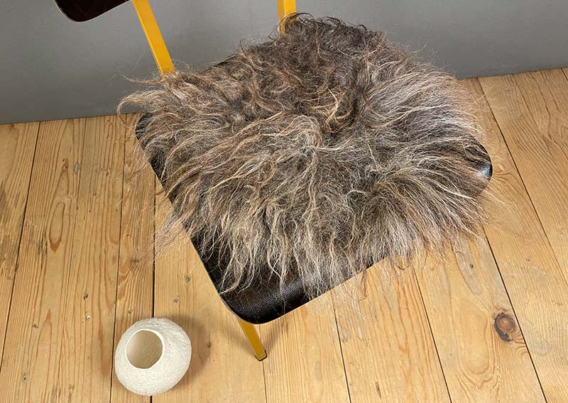 Sitzfell vom Walliser Landschaf – Schokoladenmelange mit Sonnenkuss.
Dieses Sitzfell trägt das Abenteuer schon im Fell. Langsträhnig, ungebändigt, eigenwillig schön – so, wie es eben ein Walliser Landschaf zustande bringt.

Die Farbe erinnert an Schokoladenmelange mit einem Hauch von Sonne, dort, wo die Strähnen leicht sonnengebleicht wirken. Mal schimmert es dunkelbraun, mal anthrazit – als hätte der Wind selbst den Pinsel geführt.

Das Fell ist leicht und beweglich, lässt sich wunderbar zusammenrollen und mitnehmen – sei es auf eine Wanderung, ans Seeufer oder einfach auf den Lieblingsstuhl daheim.

Kein Stück für Perfektionistinnen – aber ein echtes Stück Freiheit.