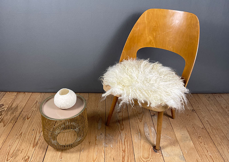 Sonnenaufgangsweiss – Sitzfell vom Walliser Schwarznasen-Schaf.
Ein bisschen wild darf’s schon sein. Dieses Fell vom Walliser Schwarznasen-Schaf bringt genau das mit: Locken, Zotteln und Charakter. Die Fasern sind unterschiedlich lang – bis zu 20 cm –, und jede Strähne scheint ihre eigene kleine Geschichte zu erzählen.

Gefilzt aus Wolle einer alten Walliser Rasse, die dort oben zwischen Felsen und Sonne zuhause ist. Wetterfest, robust und doch erstaunlich weich – so wie das Land, aus dem sie stammt.

Mit seinem grösseren Durchmesser (ca. 48 cm) passt dieses Sonnenaufgangsweiss-Fell wunderbar auf Sessel oder Stühle mit etwas mehr Platz.
Ein Stück Morgenglanz aus den Bergen – zum Sitzen, Durchatmen und die Gedanken schweifen lassen.